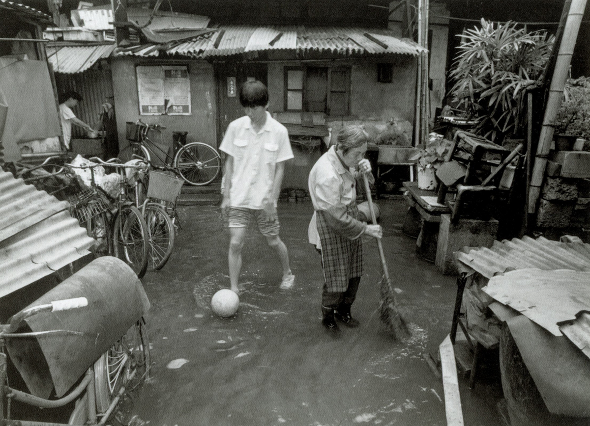 A teenager kicks a soccer ball after a rain storm on Dongchang Road, Shanghai, 1999. Courtesy of Wu Jianping