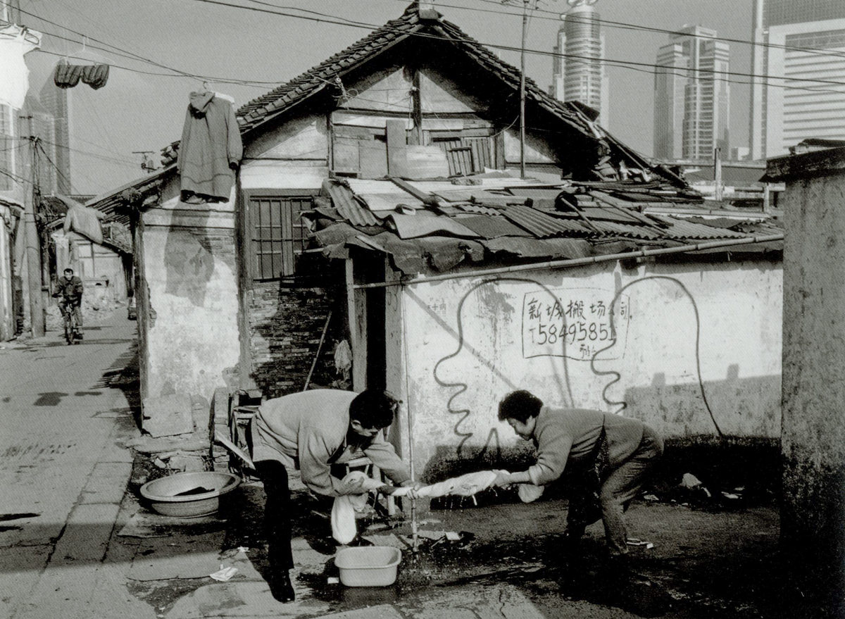 Two residents squeeze the water out of a sheet on Dongchang Road, Shanghai, 2000. Courtesy of Wu Jianping