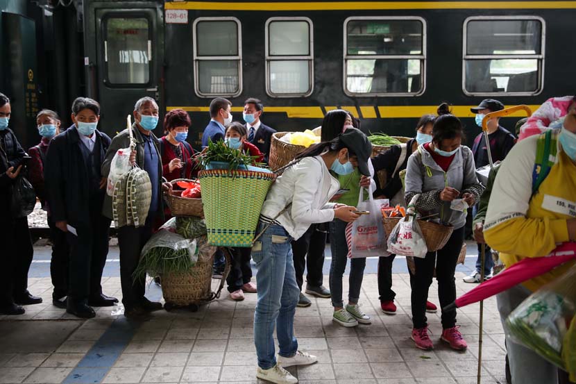 Passengers check their “health codes” as they wait in line to board trains at Tongzi Train Station in Tongzi, Guizhou province, April 16, 2020. Zhai Honglun/CNS
