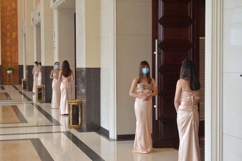 Staff wearing face masks wait for guests attending a conference in Guizhou province, April 17, 2020. People Visual