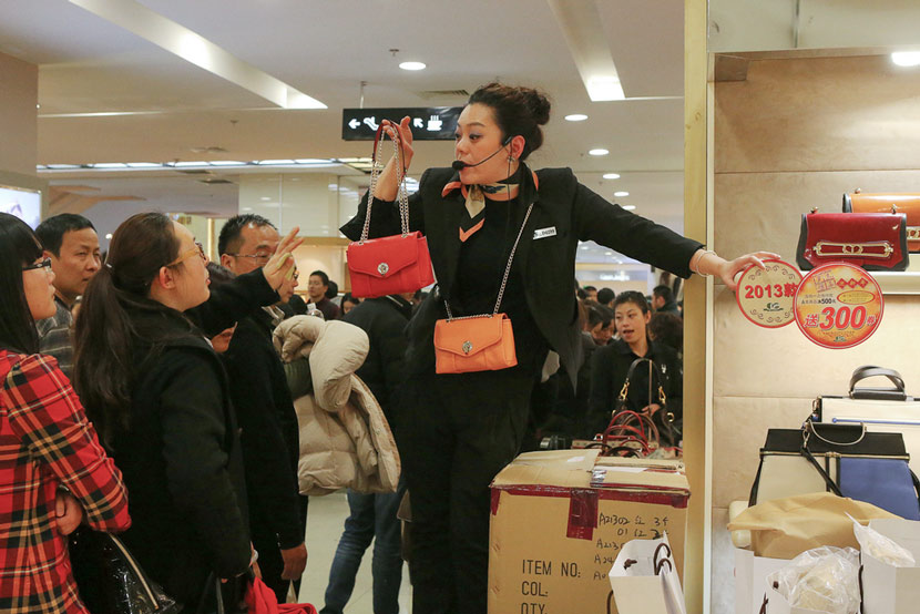A saleswoman hawks handbags at No. 1 Yaohan Department Store in Shanghai, Dec. 31, 2013. Wang Chen for Sixth Tone