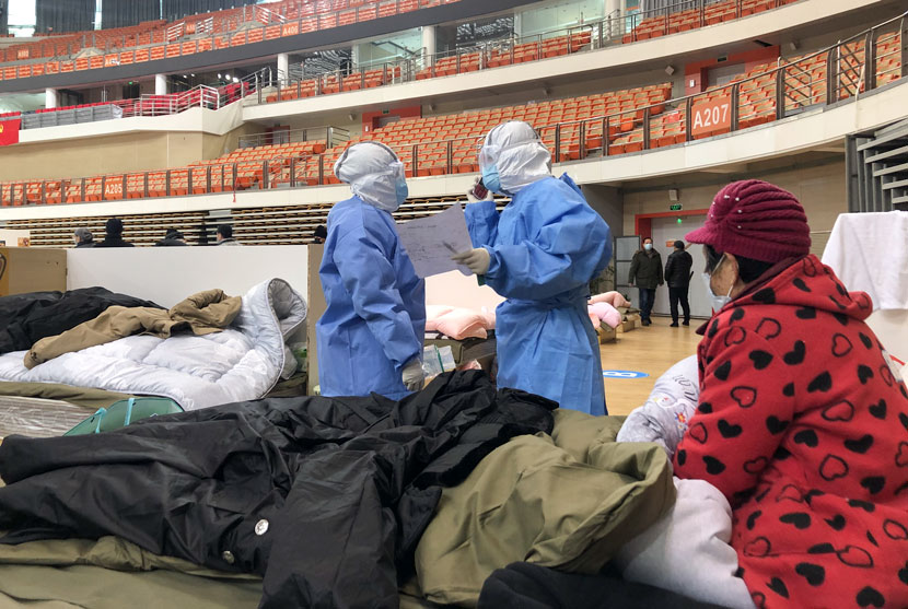 Medical workers check the condition of the elderly woman whose bed was next to Yi Bei’s, at a “fangcang” shelter hospital in Wuhan, Hubei province, February 2020. Yi Bei for Sixth Tone