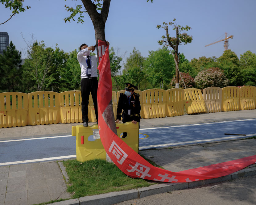 A staff member prepares to hang a banner to promote disease prevention at Wuhan’s “Optics Valley,” Hubei province, April 13, 2020. Shi Yangkun/Sixth Tone