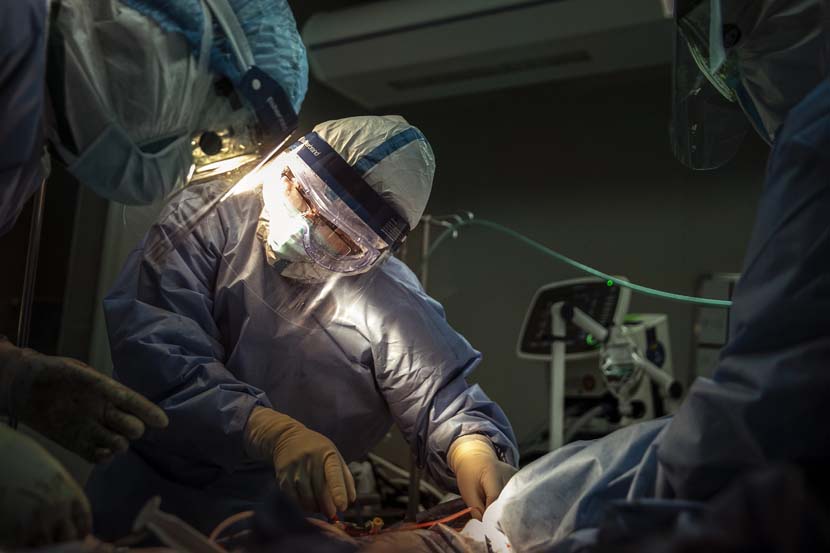 Twelve experts from six different provinces perform a VAV-ECMO diversion, a procedure for severe heart and lung failure, to a patient in shock in the Wuhan Pulmonary Hospital ICU, Hubei province, March 21, 2020. Sun Zhan for Sixth Tone