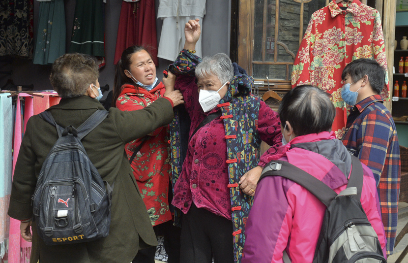 A visitor tries on a jacket at a tourist attraction in Danzhai County, Guizhou province, April 25, 2020. Qiao Qiming/People Visual