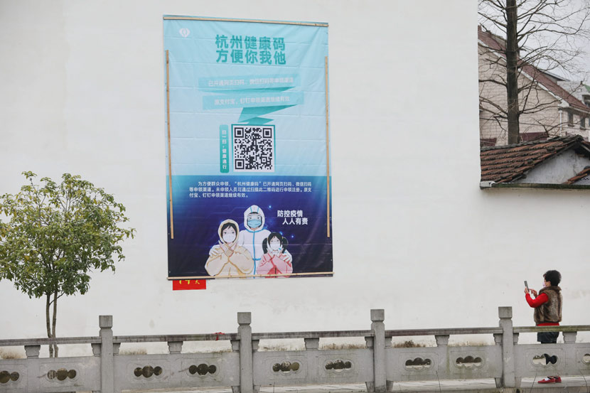 A woman scans a QR code on a poster promoting digital anti-epidemic measures in Hangzhou, Zhejiang province, Feb. 15, 2020. Hu Jianhuan via Xinhua