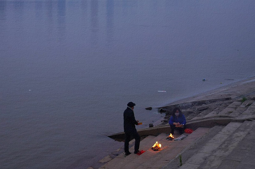 People burn paper money offerings to their deceased family members by the river in Wuhan, Hubei province, April 3, 2020. People Visual