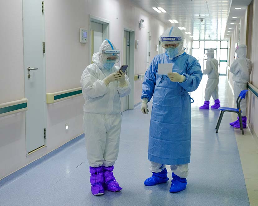 He Ping (left) exchanges information on patients with colleagues who are not on call that day at Wuhan Union Hospital (West Branch) in Wuhan, Hubei province, April 11, 2020. Shi Yangkun/Sixth Tone
