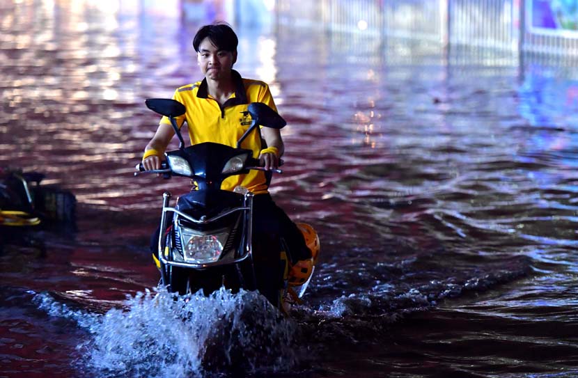 A food delivery driver drives through floodwater following heavy rain in Fuzhou, Fujian province, May 16, 2020. Zhang Bin/CNS/People Visual