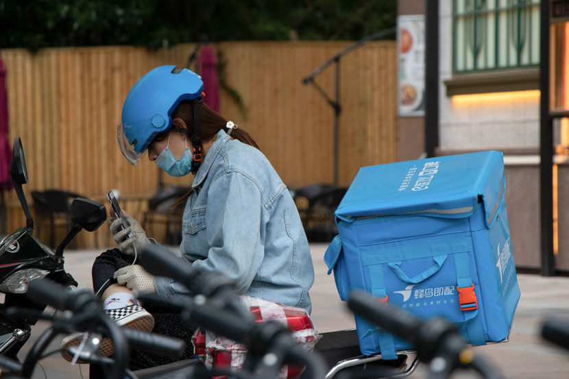 A delivery driver checks her phone, Shanghai, May 21, 2020. Over 90% of the courier workface is male. Kenrick Davis/Sixth Tone