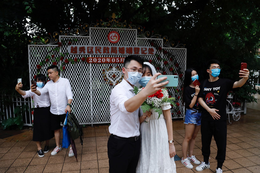 Couples pose for selfies outside the marriage registration office in Yuexiu District, Guangzhou, Guangdong province, May 20, 2020. The date, which is pronounced similar to “I love you” in Chinese, is seen as an auspicious one for getting married, especially by young Chinese. Chen Hui/Southern Metropolis Daily/People Visual