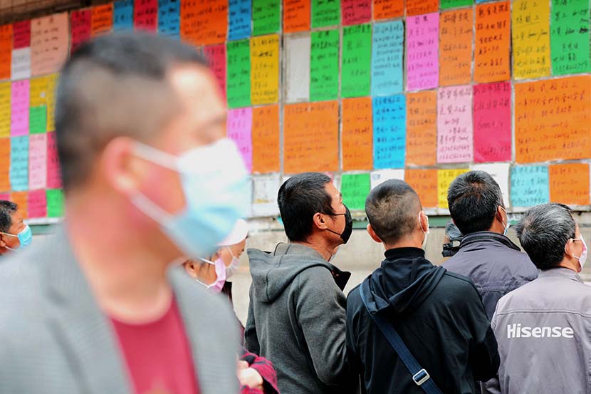 Jobseekers check job ads posted at an employment fair in Qingdao, Shandong province, April 8, 2020. People Visual
