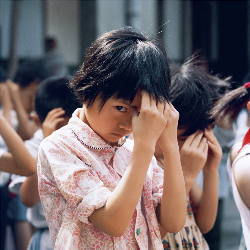 A girl steals a glance during “eye exercises,” massages for releasing eye strain, in Chengdu, Sichuan province, 1981-1982. Courtesy of Ryoji Akiyama via Seisodo