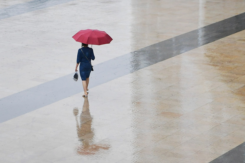 A woman walks through a square during a rainy day in Shanghai, June 3, 2020. Zhou Junxiang/IC
