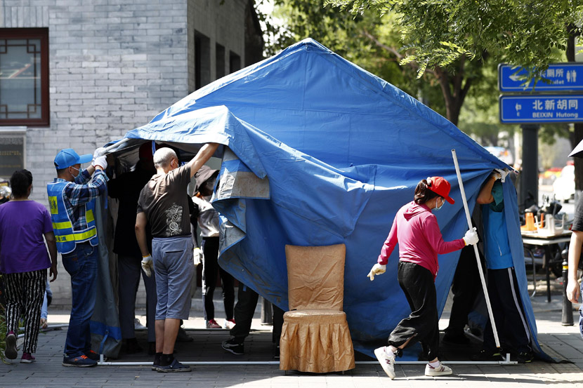 People dismantle a tent used for checking entrants’ body temperatures and registering vistors during the pandemic at a residential community in Beijing, as the capital lowered its public health emergency response level, June 6, 2020. Fu Tian/CNS/People Visual