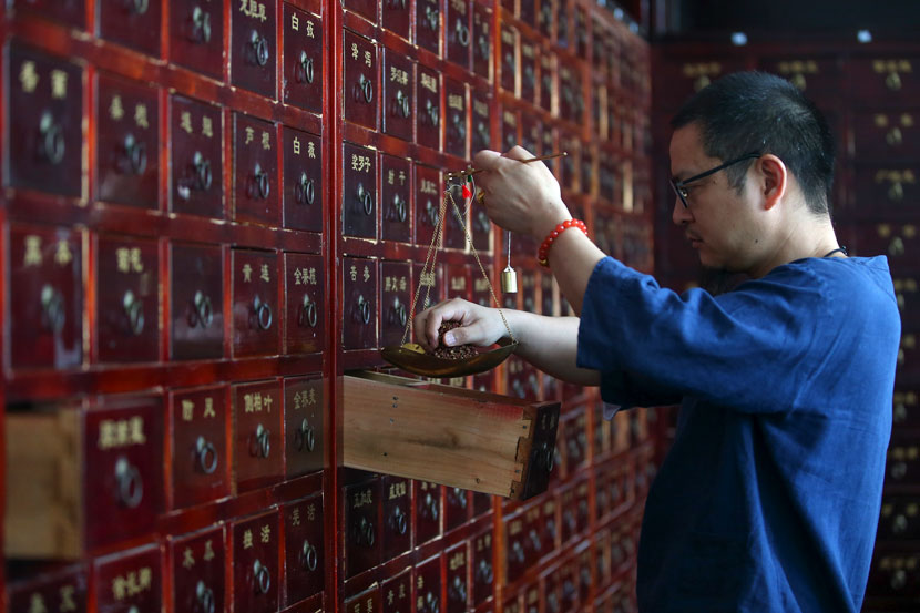 A pharmacist weighs TCM ingredients in Huangshan, Anhui province, June 5, 2019. Shi Yalei/People Visual