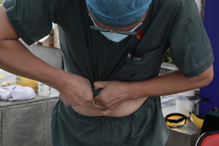 A medical worker wrings out his shirt during a break at one of the coronavirus testing sites in Beijing, June 20, 2020. Wang Weiwei/People Visual