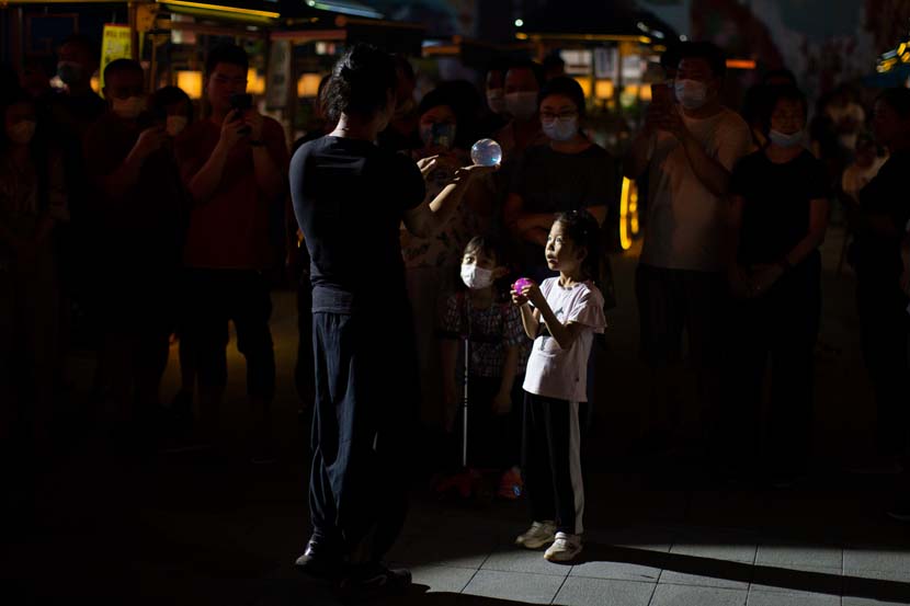 A child takes part in a performance at Yu Garden in Shanghai, June 23, 2020. With the tourism industry still feeling the effects of the coronavirus pandemic, Yu Garden launched a series of interactive attractions to lure visitors ahead of the Dragon Boat Festival. Shi Yangkun/Sixth Tone