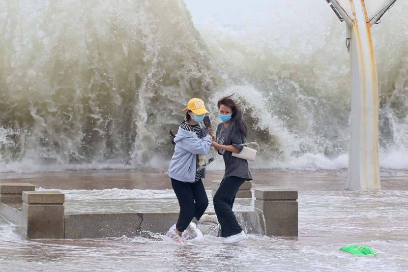 Two women run away from a large wave in Yantai, Shandong province, June 24, 2020. The city has been battered by storm surges this week. People Visual