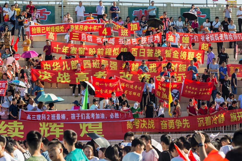 Parents of students who will soon take the “gaokao” hold banners with supportive messages at a high school in Mianyang, Sichuan province, June 5, 2019. Zhang Cheng’an/People Visual