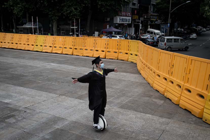A college graduate in a cap and gown wheels around Wuhan University, Hubei province, June 11, 2020. University seniors in Wuhan graduated immediately after they returned to schools. IC