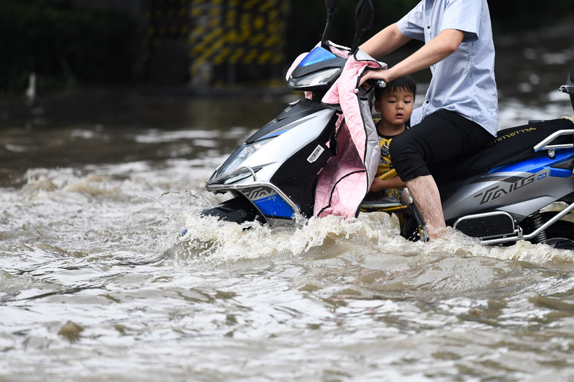 A man and child make their way down a flooded street in Zhengzhou, Henan province, July 4, 2020. IC