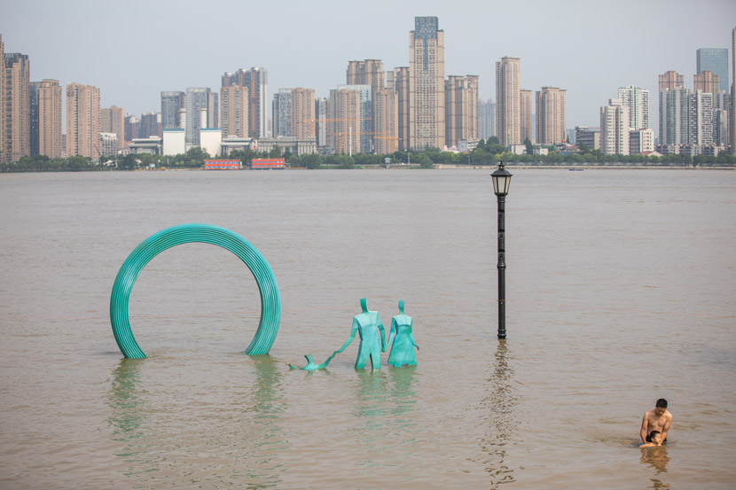 A father and son swim by the riverside in Wuhan, Hubei province, July 3, 2020. The flood-prone city was inundated again this week. People Visual