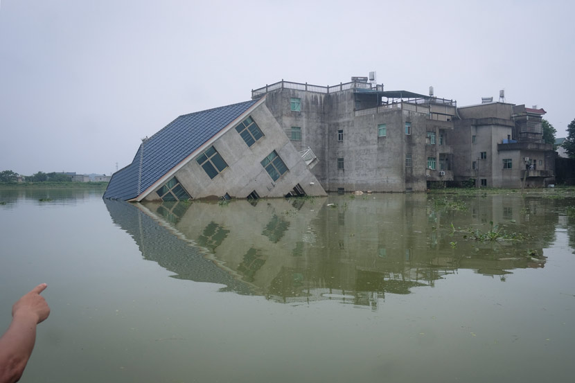 A rescue team member points toward a destroyed villa in Youdunjie Town, Poyang County, Jiangxi province, July 15, 2020. At least nine buildings and two bridges collapsed there during this year’s flood season. Wu Huiyuan/Sixth Tone
