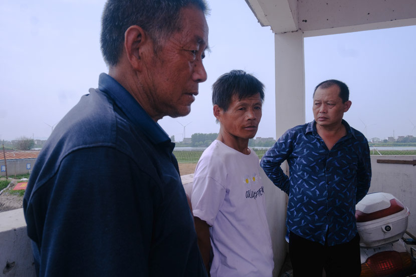 Yan Shuohan (left) works his shift monitoring the dike in Jiangzhou Town, Jiangxi province, July 14, 2020. Wu Huiyuan/Sixth Tone