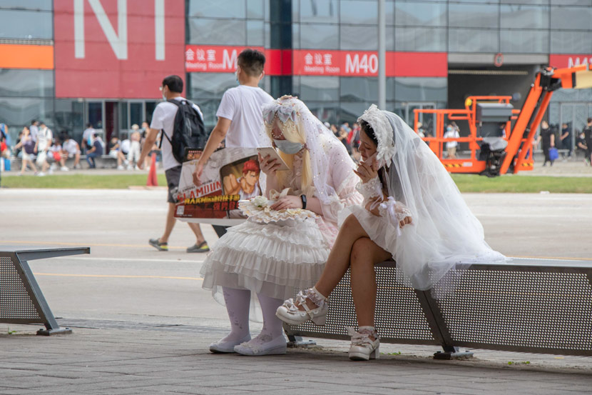 People in wedding dresses sit outside the conference venue for the ChinaJoy digital entertainment expo in Shanghai, July 31, 2020. Kenrick Davis/Sixth Tone