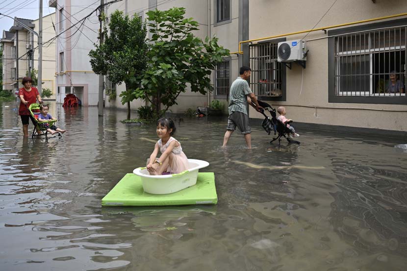 A girl sits in a bathtub floating on the floodwater in Pinghu, Zhejiang province, Aug. 5, 2020. The area was inundated after Typhoon Hagupit struck China’s southeastern coastline. Jim/People Visual