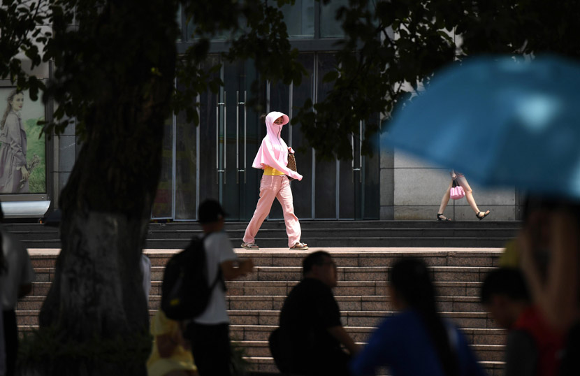 A woman in sun-protection gear walks along a road in Chongqing, Aug. 10, 2020. Chen Chao/CNS/People Visual