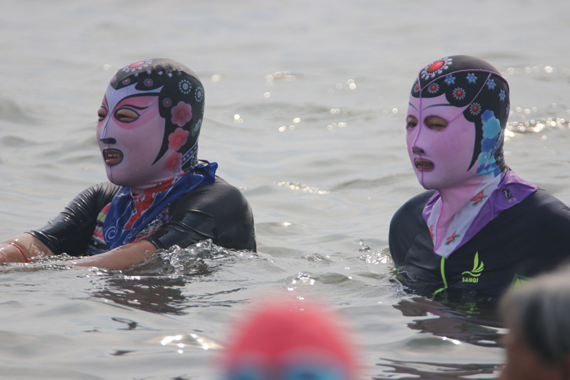 Beachgoers in “facekinis” enjoy the waters in Qingdao, Shandong province, Aug. 15, 2020. Huang Jiexian/People Visual
