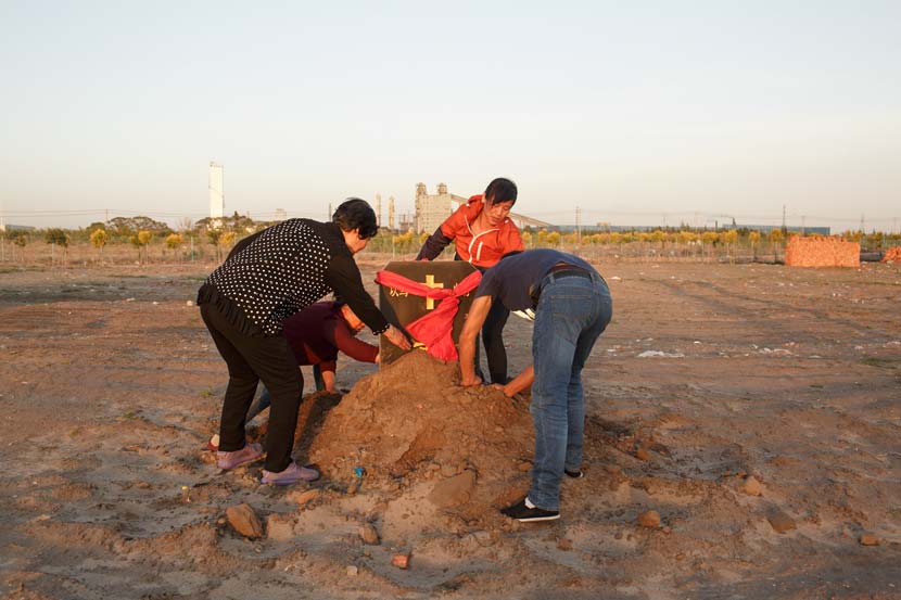 Members of a Christian church dig in the soil to uncover the cornerstone at their new church site in Tongliao, Inner Mongolia Autonomous Region, May 29, 2017. Zhou Pinglang/Sixth Tone