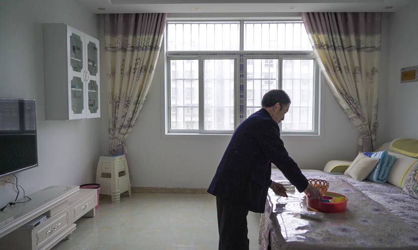 Huai Shengtang tidies his apartment in Qiyan New Village, Ankang, Shaanxi province, March 11, 2017. Chen Xi/Sixth Tone