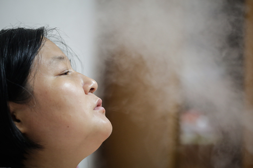 Sun Sulin breathes through the mist from a humidifier at home in Shanghai, July 6, 2017. Zhong Changqian/Sixth Tone