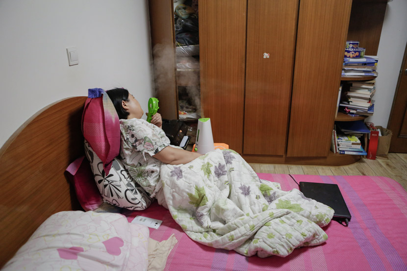 Sun Sulin uses a portable fan and a humidifier to help relieve her nasal symptoms at home in Shanghai, July 6, 2017. Zhong Changqian/Sixth Tone