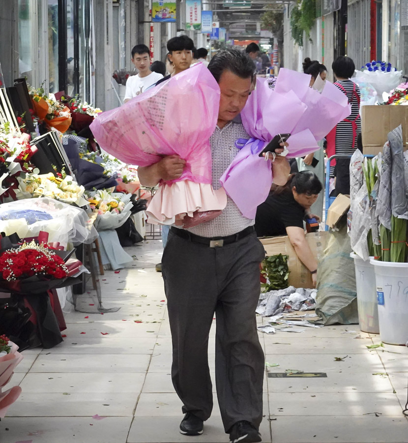 A vendor holds two bouquets of flowers during Qixi Festival at a flower market in Zhengzhou, Henan province, Aug. 25, 2020. Wang Zhongju/CNS/People Visual