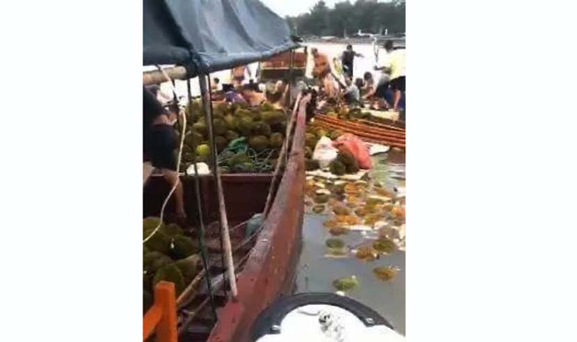A video screenshot shows villagers collecting tainted durians from a boat on a beach near Dongxing, Guangxi Zhuang Autonomous Region, Aug. 26, 2020. From Weibo