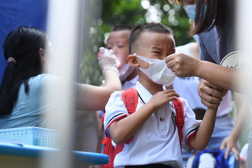 A mother helps her son wear a face mask correctly on the child’s first day of school in Chongqing, Sept. 1, 2020. Chen Chao/CNS/People Visual