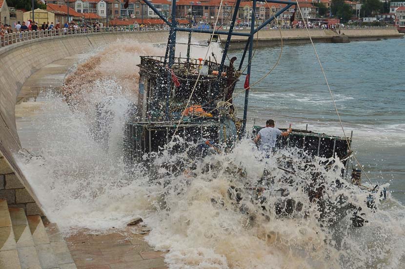 A man tries to stop a fishing boat from running into a concrete sea barrier in Qingdao, Shandong province, Sept. 2, 2020. Typhoon Maysak buffeted China’s coastal provinces with strong winds and rough seas. Wang Haibin/People Visual