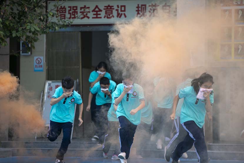 Students cover their faces as they evacuate a building during a fire drill at a high school in Xiangyang, Hubei province, Sept. 3, 2020. Su Xiaojie/People Visual