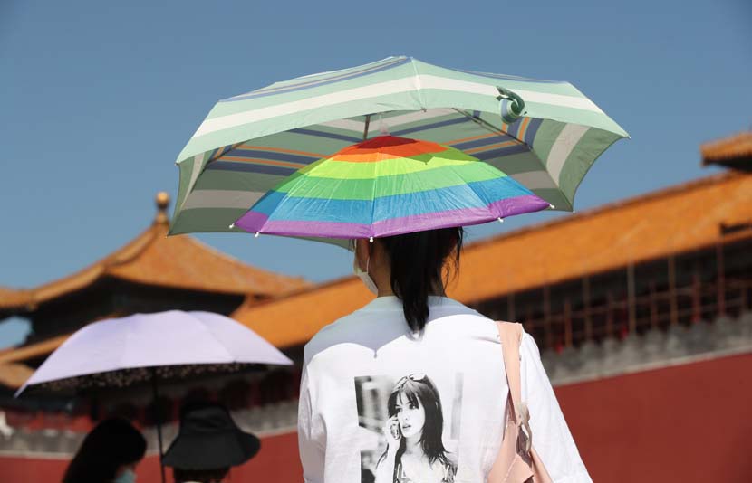 A tourist protects herself from the sun while visiting the Forbidden City in Beijing, Sept. 5, 2020. People Visual