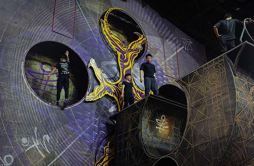 Three acrobats practice a “trampowall” act backstage at the Xintiandi Group Sun Theater in Hangzhou, Zhejiang province, July 8, 2020. As foreign acrobats specializing in trampoline stunts have been unable to reenter China, temporary local artists were hired to create a simplified version of the routine. Kenrick Davis/Sixth Tone