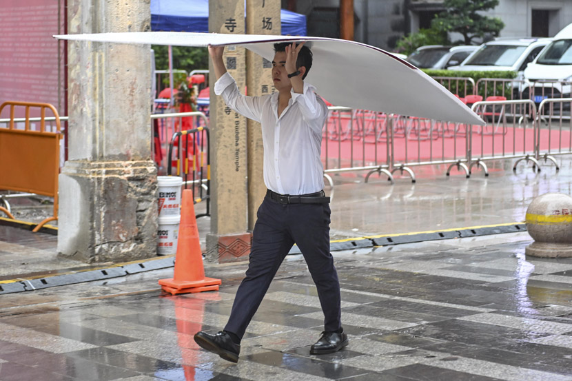 A man holds a plastic sheet to shelter from rain in Guangzhou, Guangdong province, Sept. 8, 2020. Chen Jimin/CNS/People Visual