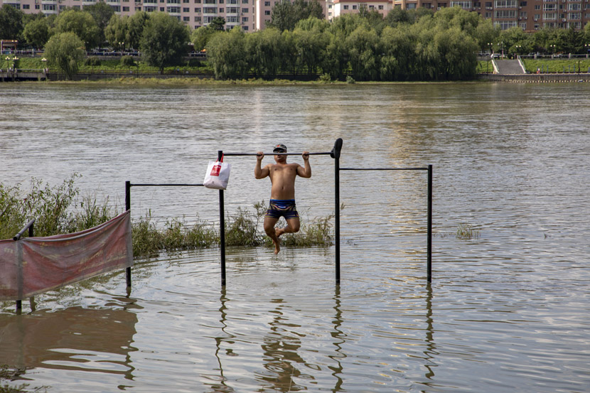 A man exercises at a flooded playground near Songhua River in Jilin province, Sept. 11, 2020. Zhu Wanchang/People Visual