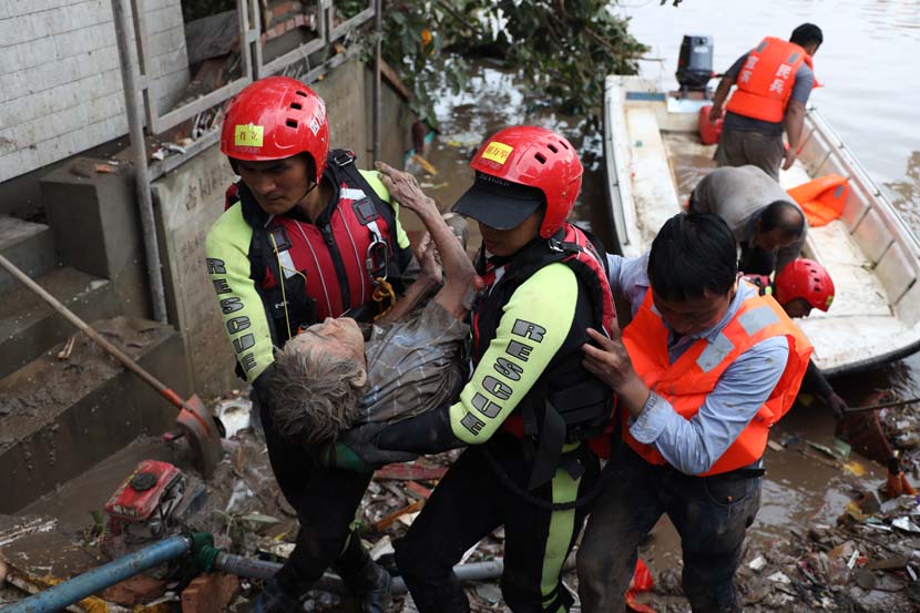 Rescuers transfer an elderly woman to a safe place after floodwaters destroy her house in Yibin, Sichuan province, Aug. 19, 2020. Wang Yushuai/People Visual