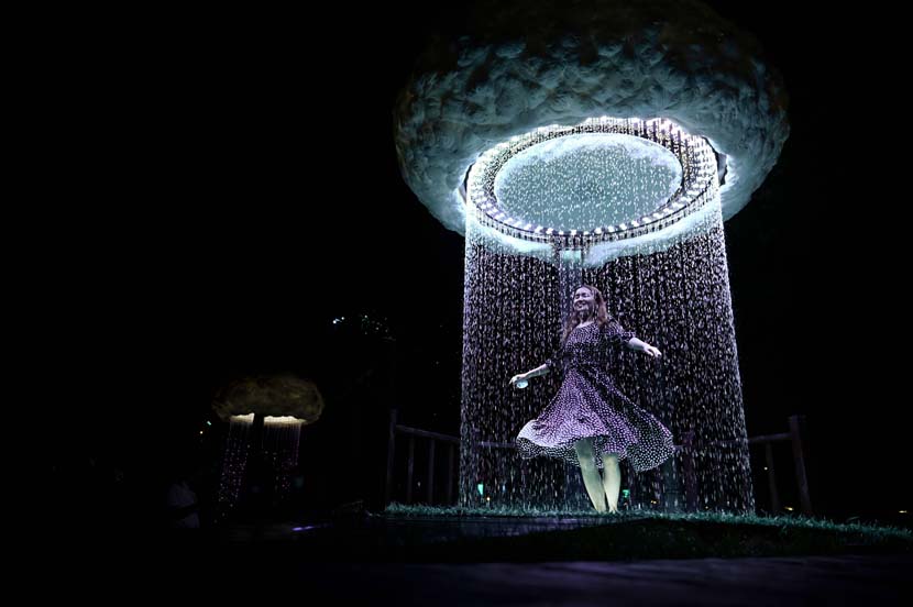A woman dances as she visits an immersive outdoor light exhibition during the 2020 Beijing International Light Festival at a park in Beijing, Aug. 22, 2020. Wang Zhao/People Visual