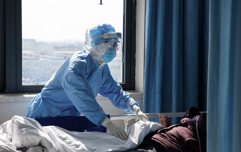 A medical worker takes care of a patient during the outbreak at Wuhan Union Hospital in Wuhan, Hubei province, Feb. 20, 2020. Xu Hao/Southern Daily/People Visual