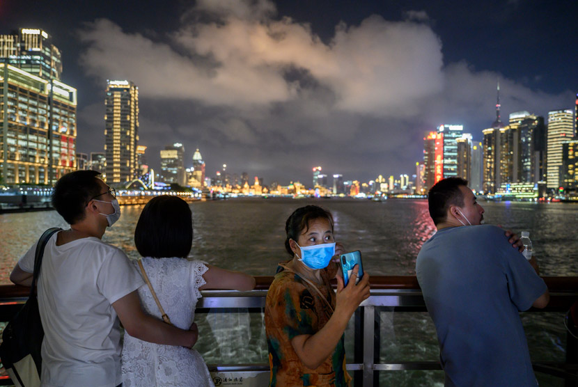 A woman wearing a face mask takes photos on the deck of a tourist boat on the Huangpu River in Shanghai, Sept. 1, 2020. Kevin Frayer/People Visual